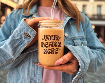 May include: A person holding a glass jar with a bamboo lid and a straw. The jar is filled with a light brown liquid and has the text "YOUR DESIGN HERE" printed on it.
