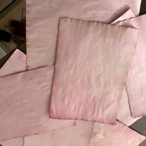 Könnte beinhalten: Mehrere Blätter rosa Papier, einige gefaltet, mit leicht strukturierter Oberfläche.