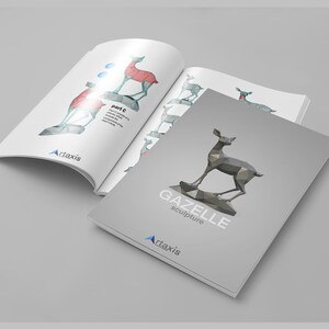May include: A gray and white booklet with the title "GAZELLE sculpture" and a geometric, polygonal, gray gazelle sculpture on the cover. The booklet is open to a page with a diagram of the gazelle sculpture, showing the different parts of the sculpture.