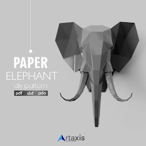 Pode incluir: Uma cabeça de elefante de papel geométrico cinza montada na parede. O texto "PAPER ELEPHANT diy pattern" está acima do elefante. Abaixo, os tipos de arquivo "pdf dxf pdo". O logotipo do artaxis studio está no canto inferior direito.