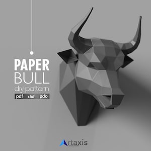 Puede incluir: Una cabeza de toro de papel geométrico en escala de grises, diseñada como un patrón de bricolaje. La imagen presenta el texto "PAPER BULL diy pattern" junto con indicadores de tipo de archivo. La cabeza del toro está en ángulo, mostrando sus cuernos y rasgos faciales.