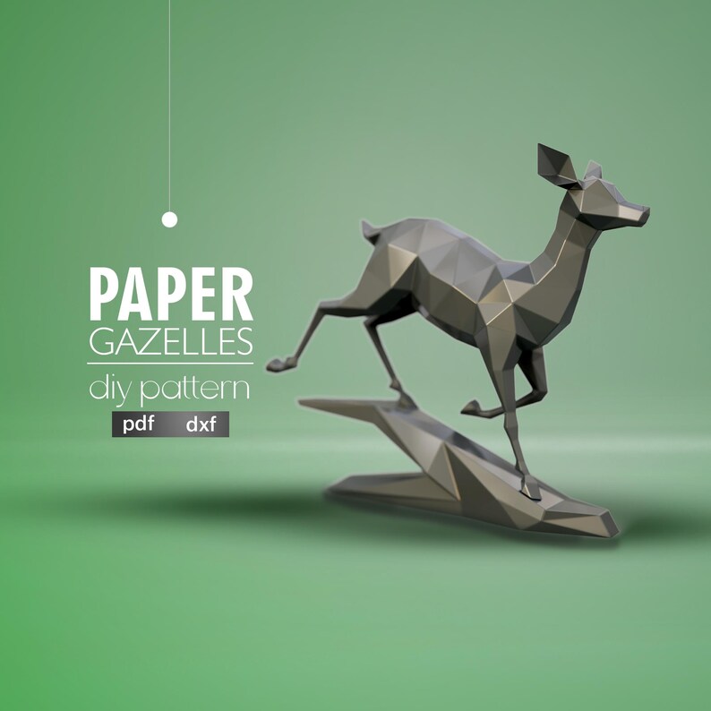 May include: A grey papercraft gazelle model in a running pose. The gazelle is standing on a grey papercraft base. The image includes the text "PAPER GAZELLES diy pattern pdf dxf".