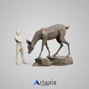 May include: A low-poly style sculpture of a deer standing on a rocky base. The deer is made of a light brown material and is in a walking pose. A person is standing to the left of the sculpture, looking at the deer.