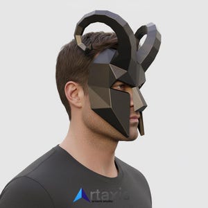 Op de afbeelding: Een zwart geometrisch masker met gebogen hoorns, dat het gezicht en het hoofd bedekt. Het masker heeft een polygonale vormgeving en wordt door een persoon gedragen. Het masker is een uniek accessoire.