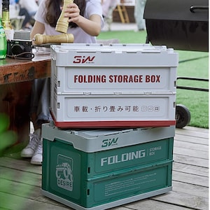 May include: A white folding storage box with red trim stacked on a green folding storage box. The white box features the text FOLDING STORAGE BOX and Japanese characters. The green box displays the text FOLDING STORAGE BOX and DESIRE OF CAR LIFE.