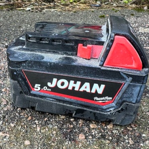 Puede incluir: Batería negra con detalles rojos y el texto "JOHAN PowerMax 5.0Ah" impreso en el lateral.