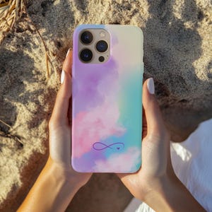 May include: A phone case with a watercolor-like design in shades of pink, purple, and blue. The case features a purple infinity symbol with a small heart in the center.