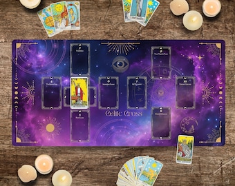 May include: A purple and gold tarot cloth with a celestial design and the words "Celtic Cross" printed in the centre. The cloth is laid out on a wooden surface with tarot cards scattered around it.