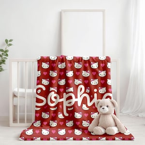 May include: Red fleece blanket with a white Hello Kitty pattern and pink hearts. The blanket has the name "Sophia" written in white cursive on it.