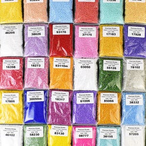 May include: Assortment of small, round, colorful beads in individual plastic bags. Each bag has a label with the brand name "Preciosa Ornela", the size of the beads, and a code number.