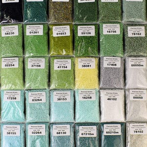 May include: Assortment of small, round, glass beads in various colors, including green, blue, white, and yellow. Each bag contains 10/0 size beads and is labeled with a number and the brand name "Preciosa Ornela".