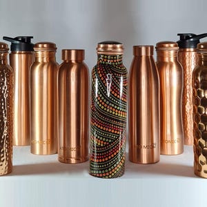 K&ouml;nnte beinhalten: Eine Sammlung von Kupfer-Wasserflaschen mit verschiedenen Designs und Oberfl&auml;chen. Die Flaschen sind alle gleich gro&szlig; und haben die gleiche Form, aber unterschiedliche Muster und Texturen. Einige der Flaschen haben eine glatte Oberfl&auml;che, w&auml;hrend andere eine geh&auml;mmerte oder strukturierte Oberfl&auml;che haben. Die Flaschen sind alle aus Kupfer gefertigt und haben eine gl&auml;nzende Oberfl&auml;che.