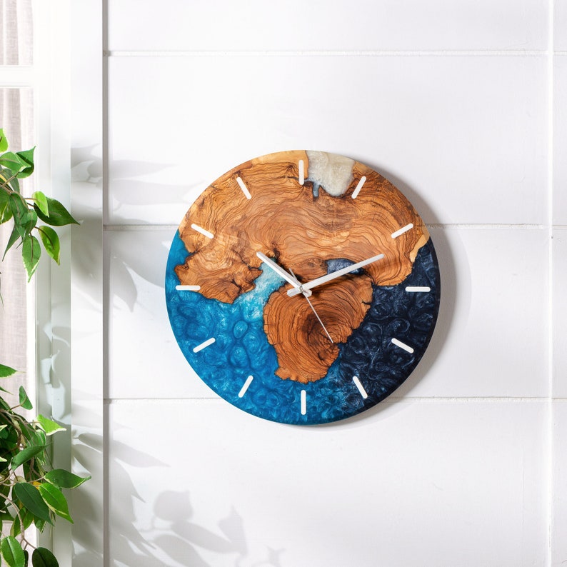 May include: A round wall clock with a blue and brown resin face. The clock has white hands and white numbers around the edge.