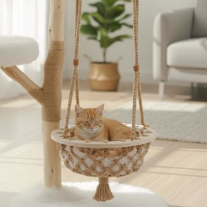 May include: A cat tree with a hanging cat bed. The cat bed is made of woven rope and wood, suspended by braided rope. An orange tabby cat is resting in the bed. The cat tree has a natural wood finish and is set on a white rug.