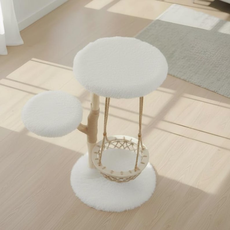 May include: A white cat tree with a round base and two platforms. The platforms are covered in soft, fluffy material. A woven basket hangs from the top platform, suspended by rope. The tree has a natural wood-colored post.