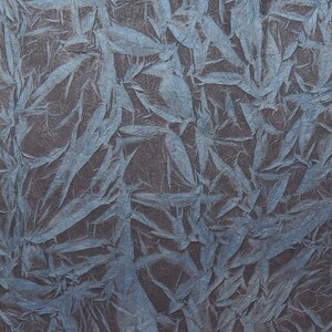 May include: A sheet of textured paper with a blue and gray pattern. The paper is folded in half and has a smaller piece of the same paper folded on top of it.