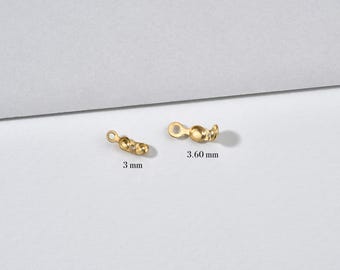 May include: Two small, gold-colored jewelry clasps. One clasp is 3 mm long, and the other is 3.60 mm long. Each clasp has a loop on one end and a rounded, decorative design on the other end. The clasps are on a light gray background.