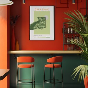 Hanging on the wall of a vibrant orange bar, there is a green color poster with a hand holding a photo-effect Gin Tonic cocktail. There is a shelf with alcohol bottles on the right side of the bar and two green bar chairs in front of it