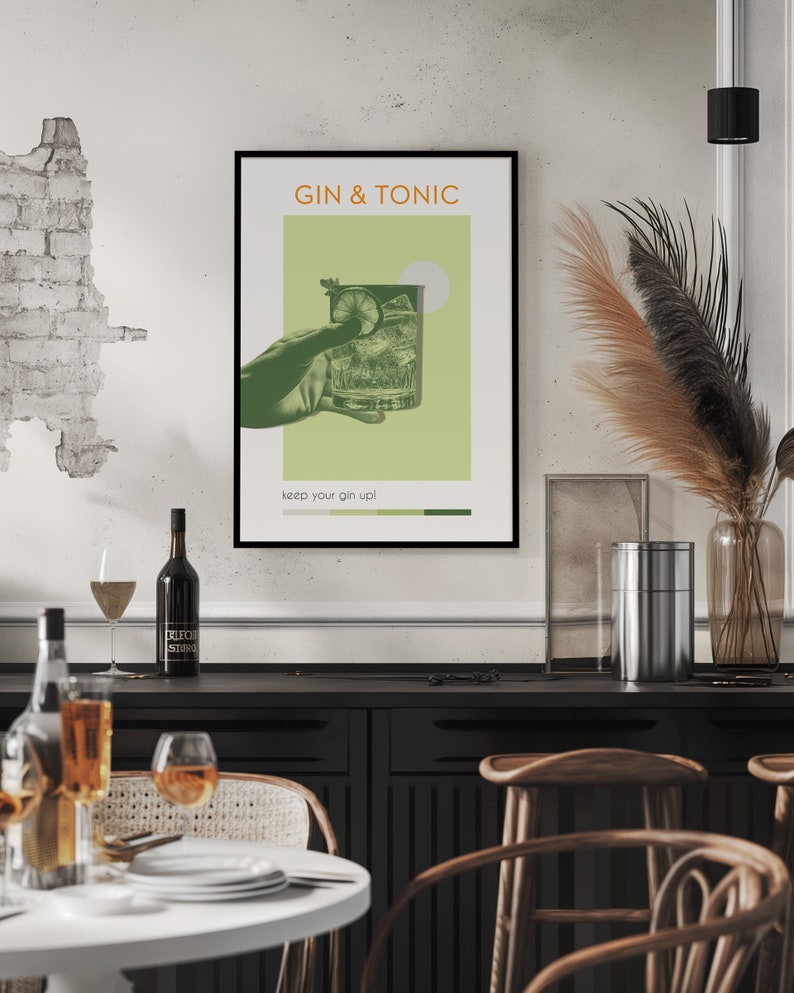 A minimalist Gin Tonic cocktail poster with a green color, also carrying a retro vibe, created using an image of a hand holding a classic cocktail glass, with photo effects, is hanging on a white dining room wall, within a black frame