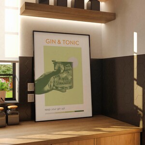 The green color Gin Tonic print, retro vibe effects, a hand holding a cocktail glass, leaning against the wall on the counter in front of the kitchen window of a modern minimalist house. There are tiny flowers and jars of coffee on the side.