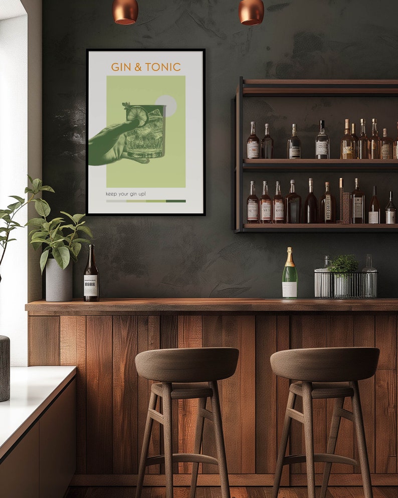 The green color Gin Tonic print, carries retro vibe effects, a hand holding a cocktail glass, hanging on a wall on the counter in front of the modern minimalist bar. There are cocktail bottles, plants, and brown bar stools on the side