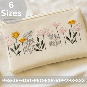 May include: Cream-colored zippered pouch with an embroidered floral design. The embroidery features yellow and pink flowers, gray foliage, and black stems. The text "6 Sizes" is in a circle at the top. A small strap is attached to the side.
