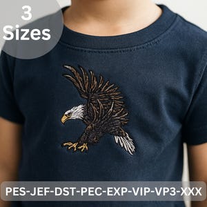 Może przedstawiać: Granatowa koszulka z haftowanym orłem w locie. Orzeł ma brązowe i białe pióra, żółty dziób i żółte szpony. Tekst "3 Rozmiary" znajduje się w białym okręgu. Na dole koszulki znajduje się napis "PES-JEF-DST-PEC-EXP-VIP-VP3-XXX".