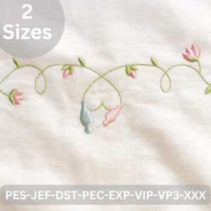 Może przedstawiać: Haftowany wzór kwiatowy z różowymi kwiatami, zielonymi liśćmi oraz jasno-niebieskim i różowym elementem dekoracyjnym na białym tle. Tekst "2 Sizes" znajduje się w okręgu na górze. Dolny tekst brzmi "PES-JEF-DST-PEC-EXP-VIP-VP3-XXX".