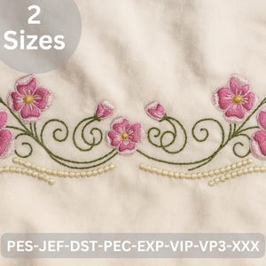 May include: Embroidered floral design featuring pink flowers with yellow centers and green stems. The design includes decorative swirls and a beaded border. The text "2 Sizes" is in a circle. The bottom of the image has the text "PES-JEF-DST-PEC-EXP-VIP-VP3-XXX".