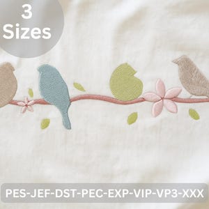 Peut inclure: Motif brodé avec quatre oiseaux perchés sur une branche avec des feuilles et des fleurs. Les oiseaux sont dans des tons de beige et de bleu, avec des feuilles vertes et des fleurs roses. Le texte "3 Sizes" est dans un cercle en haut. Le texte en bas indique "PES-JEF-DST-PEC-EXP-VIP-VP3-XXX".
