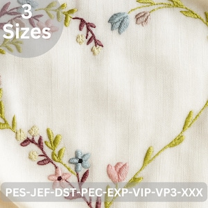 May include: Embroidered floral heart design in green, pink, blue, and burgundy on white fabric. The text "3 Sizes" is visible. The bottom of the image contains the text "PES-JEF-DST-PEC-EXP-VIP-VP3-XXX".