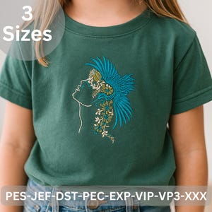 May include: A teal green t-shirt featuring an embroidered design of a woman's profile with floral and feather accents in teal, white, and yellow. The text "3 Sizes" is in a white circle. The bottom of the shirt has the text "PES-JEF-DST-PEC-EXP-VIP-VP3-XXX".