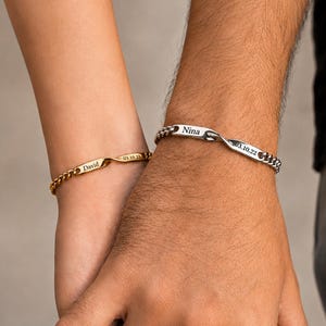 May include: A gold-toned chain bracelet engraved with the name David and a date, and a silver-toned chain bracelet engraved with the name Nina and a date. Both bracelets feature a central twisted metal bar design with personalized text.
