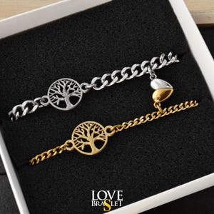 May include: Two chain bracelets, one silver-toned and one gold-toned, each featuring a circular tree of life charm. A small, two-toned heart charm connects the two chains. The text "LOVE BRASLET" is printed in white and yellow at the bottom.