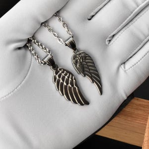 May include: Two silver-toned wing pendant necklaces. Each necklace features a detailed wing charm suspended from a delicate chain. The pendants are displayed against a white background, highlighting the intricate design and metallic finish.