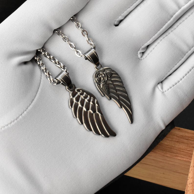 May include: Two silver-toned wing pendant necklaces. Each necklace features a detailed wing charm suspended from a delicate chain. The pendants are displayed against a white background, highlighting the intricate design and metallic finish.