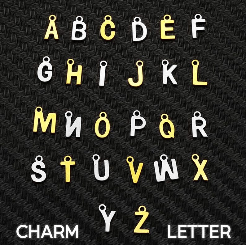 May include: A collection of alphabet letter charms arranged in rows. Each letter features a small circular loop at the top for attachment. The charms alternate between a metallic gold finish and a silver finish, displaying the full alphabet from A to Z.