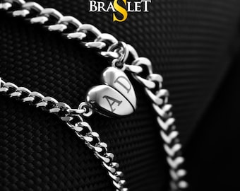 Peut inclure: Deux bracelets en chaîne argent avec un pendentif en forme de cœur gravé des lettres "AD". Les bracelets sont sur un fond noir. Le texte "LOVE BRACELET" est au-dessus des bracelets.