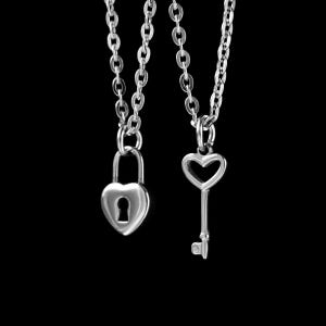 May include: Two silver necklaces, one with a heart-shaped padlock pendant and the other with a heart-shaped key pendant.