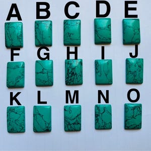 May include: Sixteen rectangular turquoise stones with dark veining, arranged in four rows of four and labelled A to O. The turquoise colour varies slightly across the stones. Each stone is a unique shape and pattern.