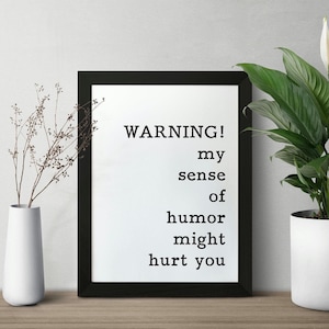 May include: Black framed print with white background and the text "WARNING! my sense of humor might hurt you".