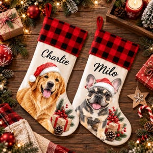 May include: Two cream-coloured Christmas stockings featuring a red and black buffalo plaid cuff. The left stocking displays the name Charlie above a golden retriever wearing a Santa hat. The right stocking shows the name Milo above a French bulldog.