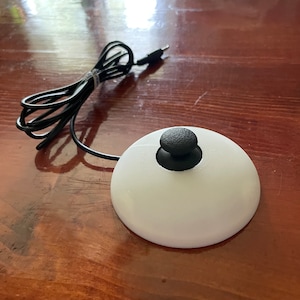 May include: A white, round, 3D printed joystick with a black knob on top. The joystick is connected to a black cord.