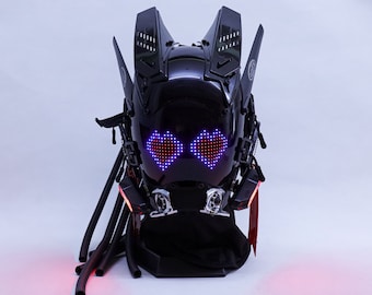 May include: A black helmet with a futuristic design, featuring LED lights shaped like hearts. The helmet has a black base and long black cords hanging down.