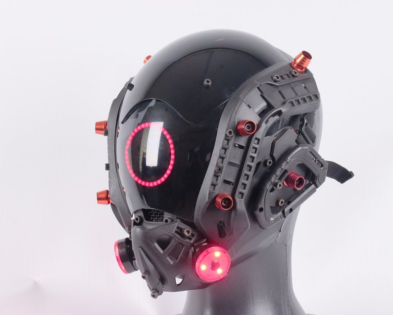 May include: A black helmet with red lights and a black and gray face mask. The helmet has a clear visor and multiple red accents.