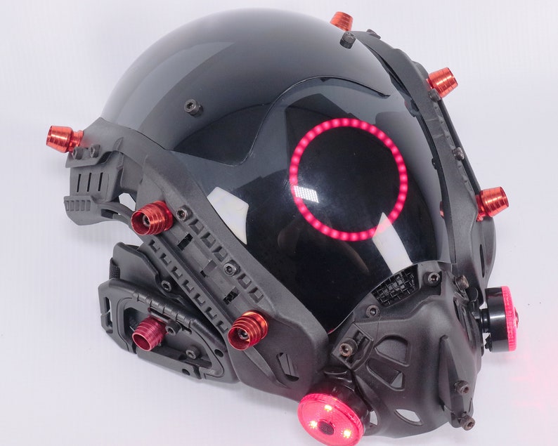May include: A black helmet with a red light ring and multiple red accents. The helmet has a visor and a face mask.