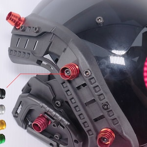 May include: A black helmet with red and silver accents. The helmet has a variety of attachments, including a visor, a chin guard, and a side mount. The helmet is designed for tactical use.