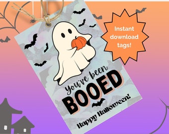 Puede incluir: Una etiqueta con temática de Halloween con un fantasma de dibujos animados sosteniendo una calabaza. La etiqueta dice "You've been BOOED" y "Happy Halloween!" con un fondo de murciélagos y un degradado naranja y morado.