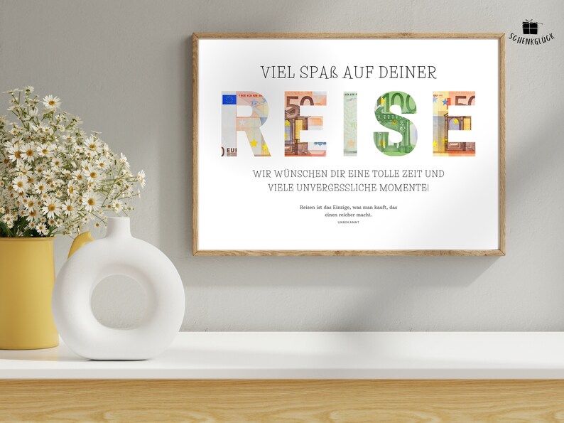 Geldgeschenk Reisekasse in einem Holzbilderrahmen hängt an einer beigen Wand über einem Sideboard. Auf dem Sideboard stehen eine Pflanze in einem gelben Blumentopf sowie eine weiße Vase.
