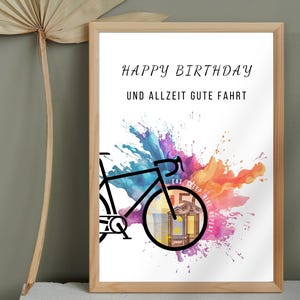 Geldgeschenk Fahrrad Geburtstag in einem Holzbilderrahmen vor einer grünen Wand neben einem getrockneten Palmenblatt